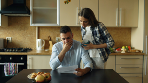 Couple reviewing overdue bills and tax documents with worried expressions